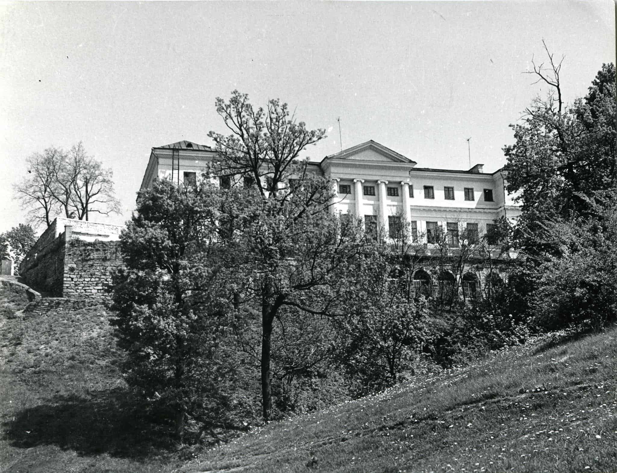 Історична будівля у Мурованих Курилівцях серед дерев.