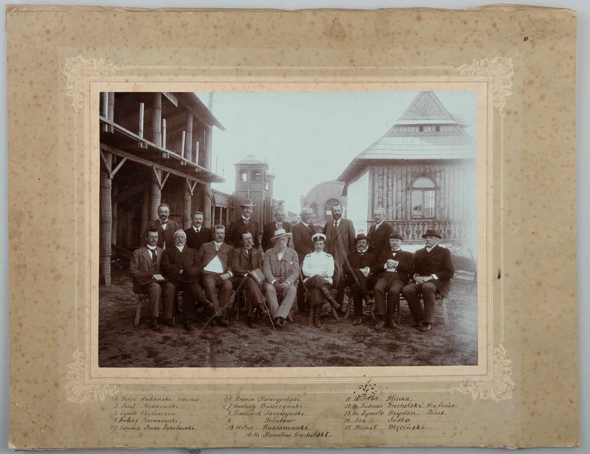 Групова фотографія в селі з дерев'яними будинками, 19 століття.