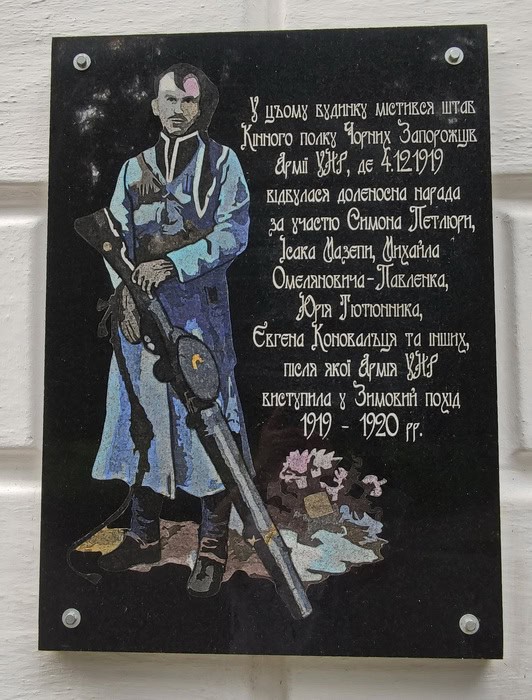 Пам'ятна дошка з портретом українського військового та історичним текстом.