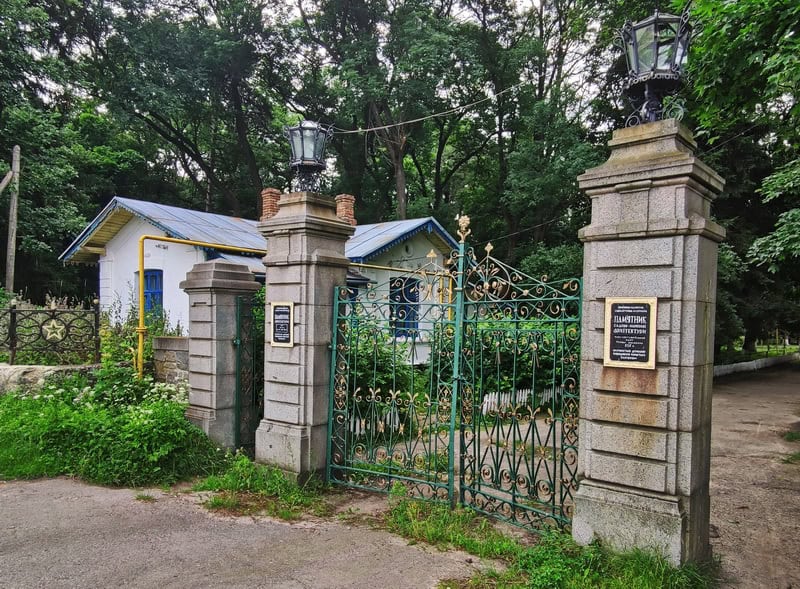 Вхід до історико-просвітнього проекту Портал з кованими воротами та освітлювальними ліхтарями.
