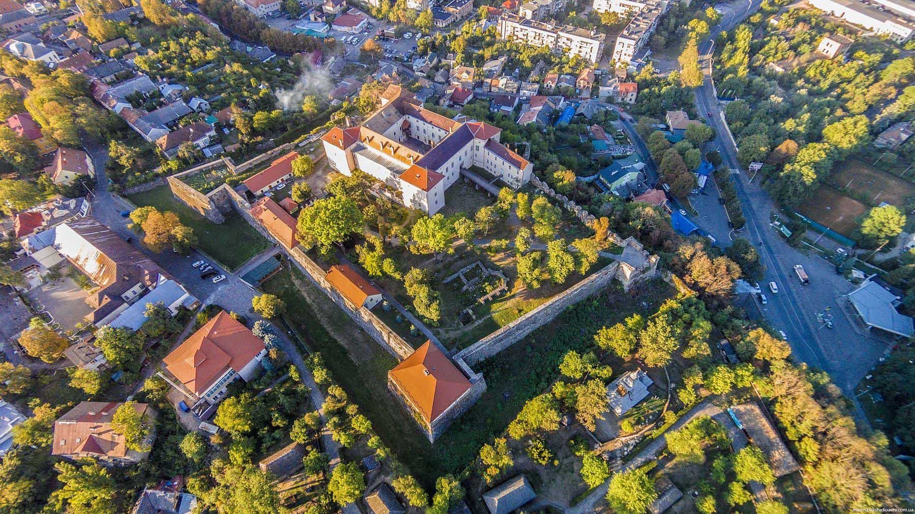 Ужгородський замок з висоти пташиного польоту, оточений зеленню та історичними стінами.