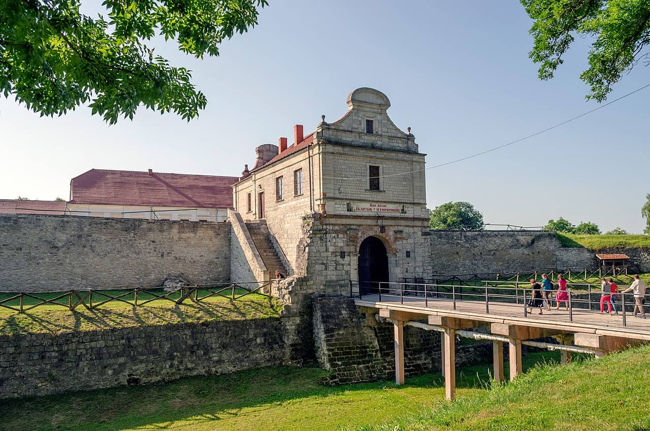 Збаразький замок з історичними стінами та входом, оточений зеленню.