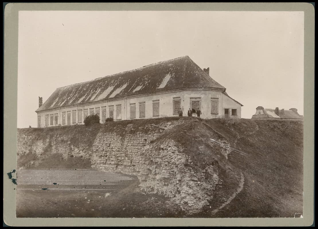 Історична фотографія Збаразького замку з старовинним будинком на пагорбі.