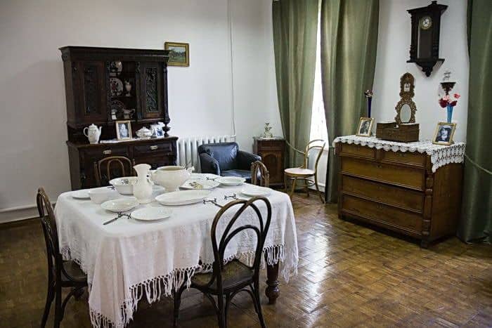 Старовинна вітальня з обіднім столом, сервірованим для сімейної вечері, з антикварними меблями.