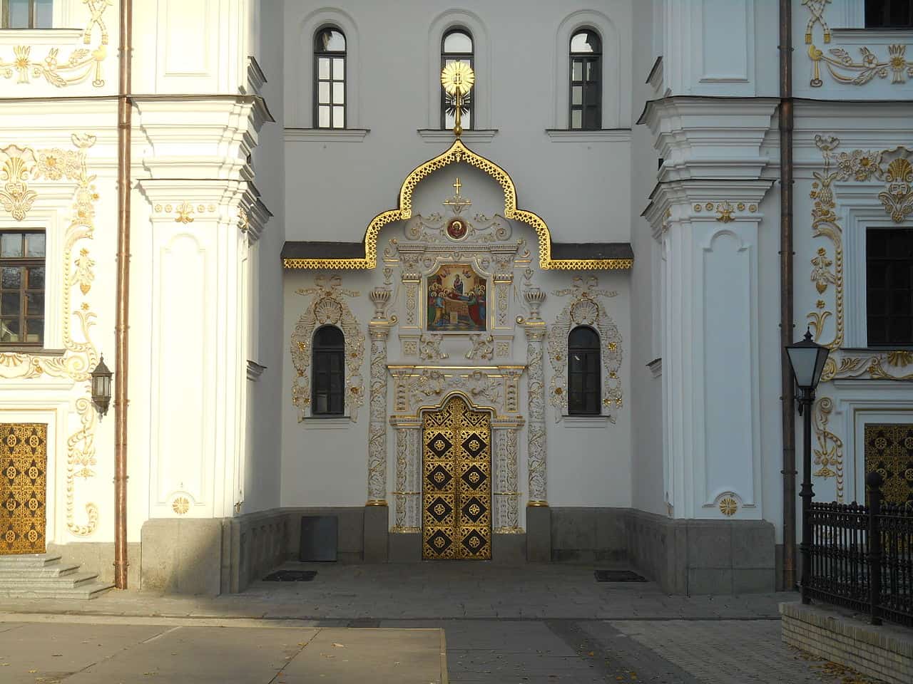 Фасад церкви з білими стінами та золотими деталями, архітектура в стилі бароко.