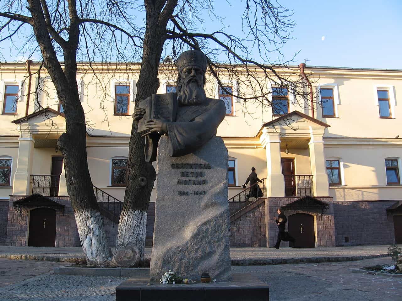 Пам'ятник Петру Могилі на фоні будівлі та дерев у Києві.