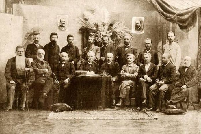 Групова фотографія в історичному інтер'єрі з чоловіками у 19 столітті.