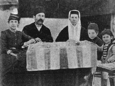 Групове фото сім'ї з 5 осіб навколо столу, чорнобіле, історична фотографія.