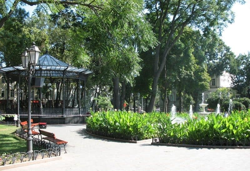 Зелений парк з лавками, ліхтарями та павільйоном у центрі Одеси.