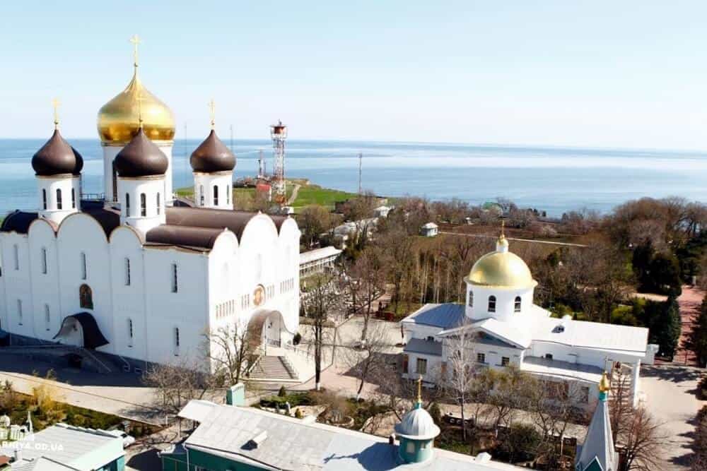 Кафедральний собор у Одесі з золотими куполами на фоні моря.