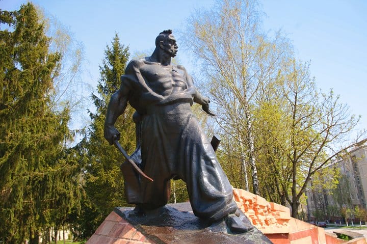 Пам'ятник Северину Наливайку на відкритому повітрі з деревами та будівлями на задньому плані.
