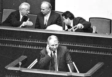 Чотири чоловіки у парламентській залі, один з них говорить, інші слухають.