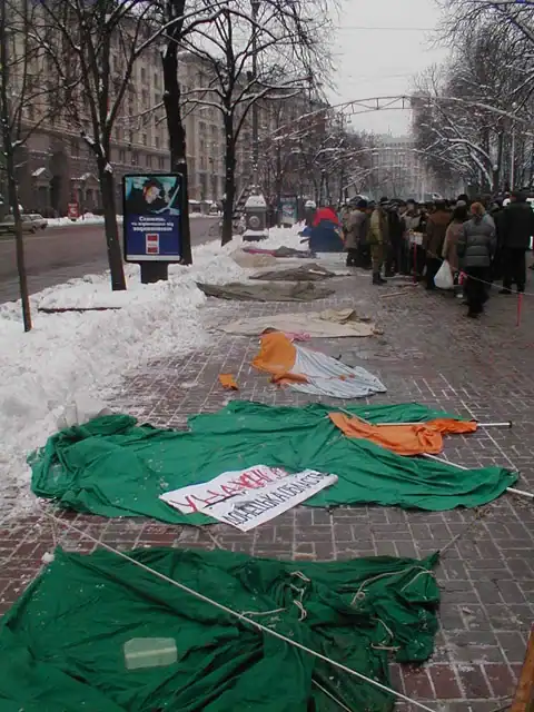 Зруйновані намети та прапори на засніженій вулиці під час протесту.