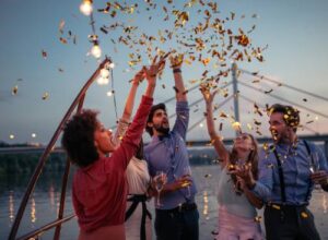 Group celebrating on yacht with confetti during sunset, perfect for bachelor parties.