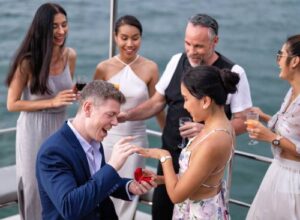Man proposes marriage to woman on a yacht during a celebration with friends.