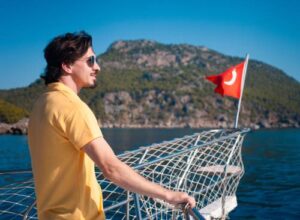 Man enjoying yacht rental experience in Göcek with scenic mountain views.