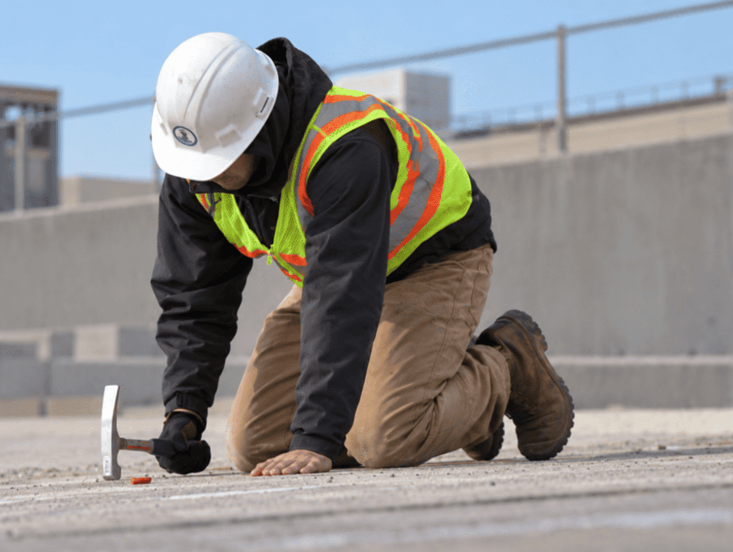 Technician tapping a concrete surface with a hammer during sounding inspection