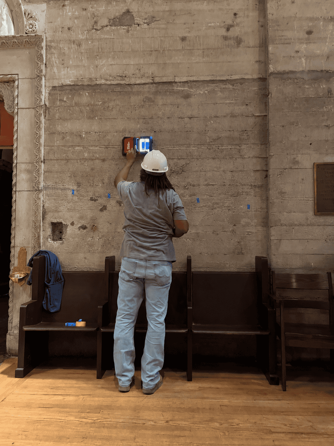 Technician wearing a hard hat operating a concrete wall scanning instrument.