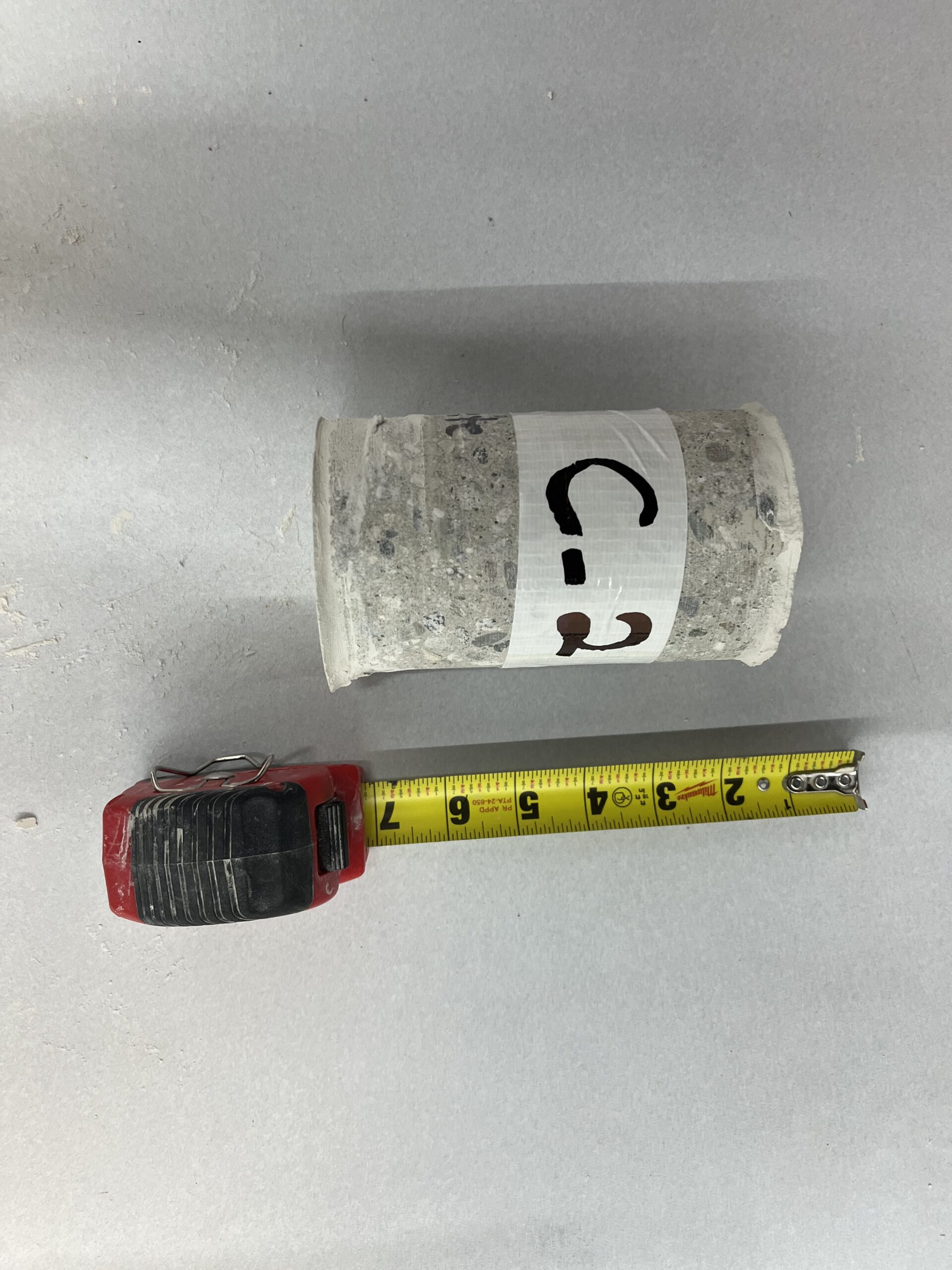 Concrete core sample labeled C-2 measured with a tape measure
