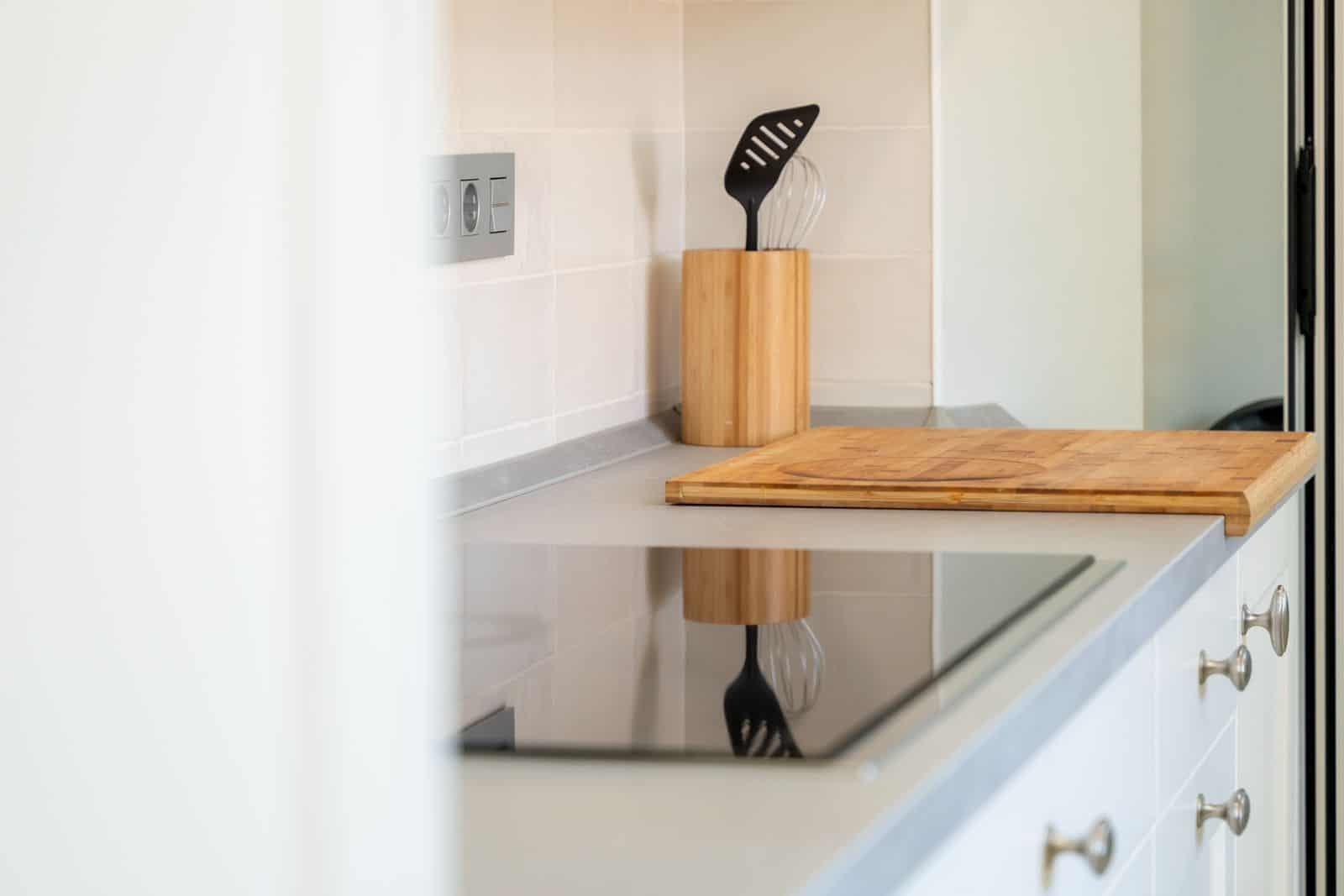 Bucătărie modernă cu plită cu inducție și accesorii din lemn.