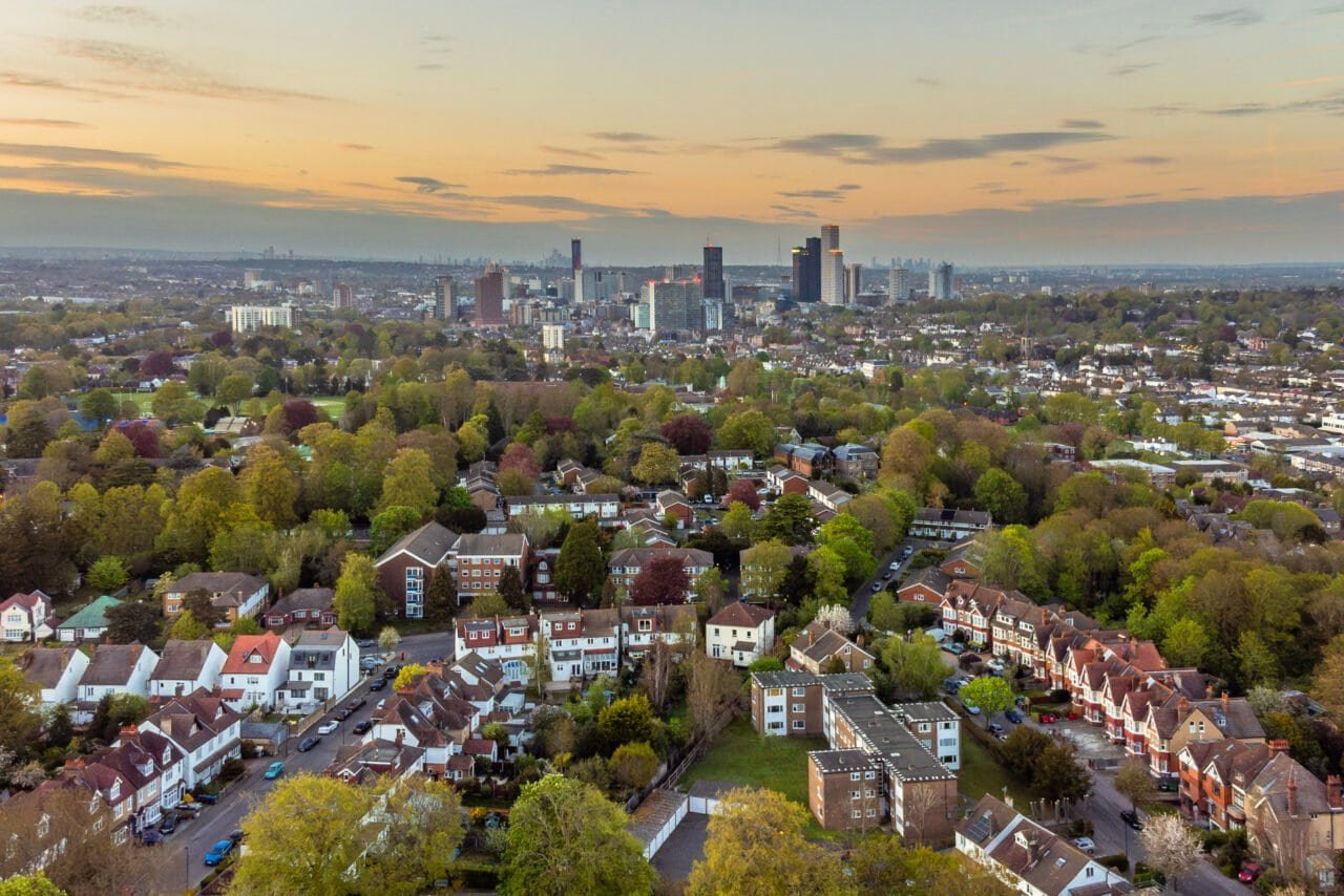 Aerial view of a city skyline with residential neighbourhoods and green spaces at sunset.