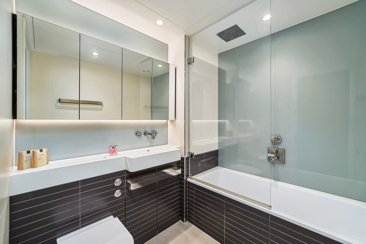 A modern bathroom with a bathtub, glass shower enclosure, and sleek fixtures.