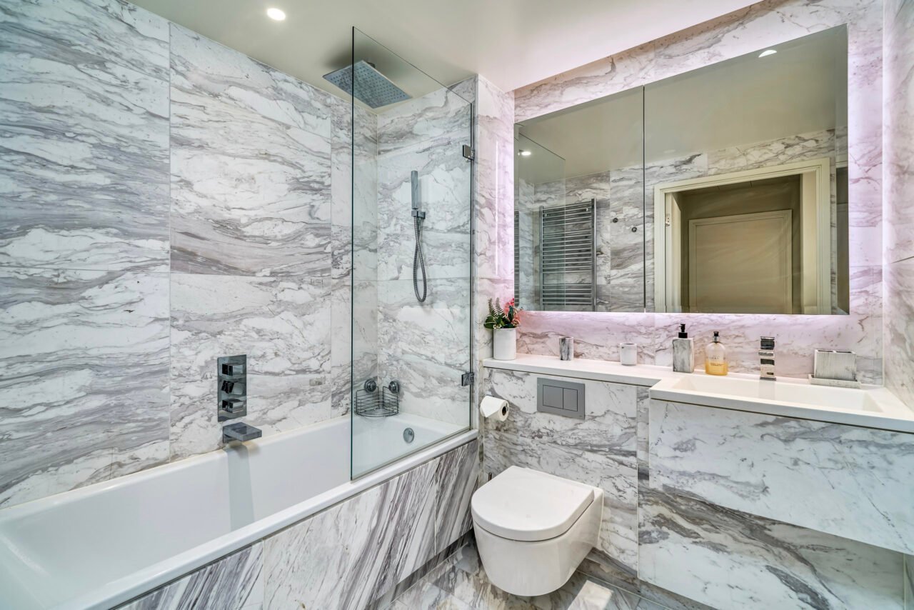 A luxurious marble bathroom with bathtub, toilet, and large mirror in modern design.