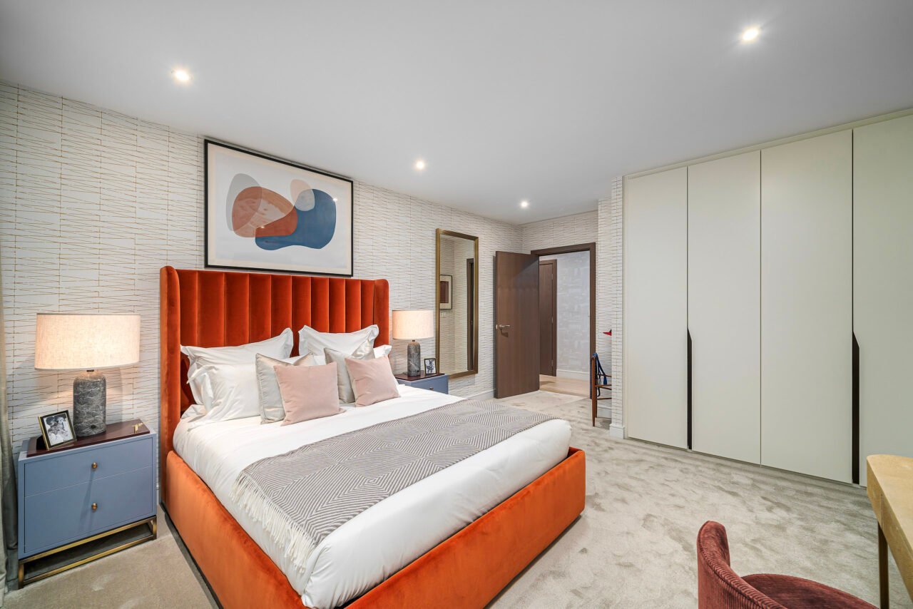 A lush modern bedroom with an orange velvet bed frame, minimalist decor, and built-in wardrobe.