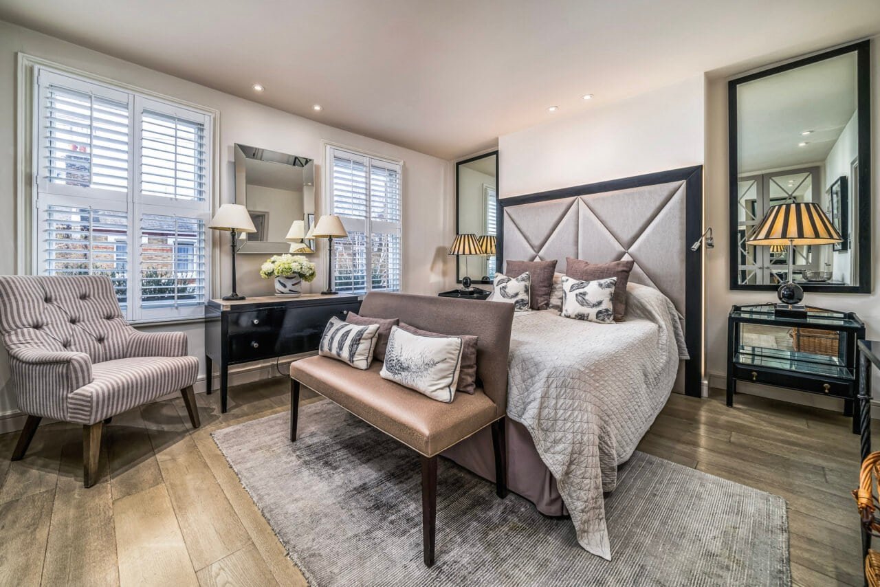 A cosy, modern bedroom with large windows, stylish furniture, and elegant decor.