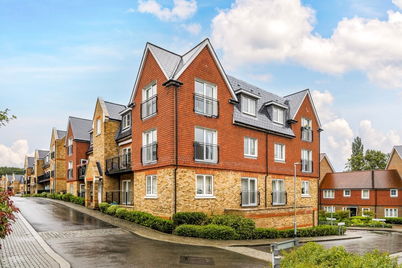 Modern residential apartment building with brick and stone exterior in a suburban neighbourhood.