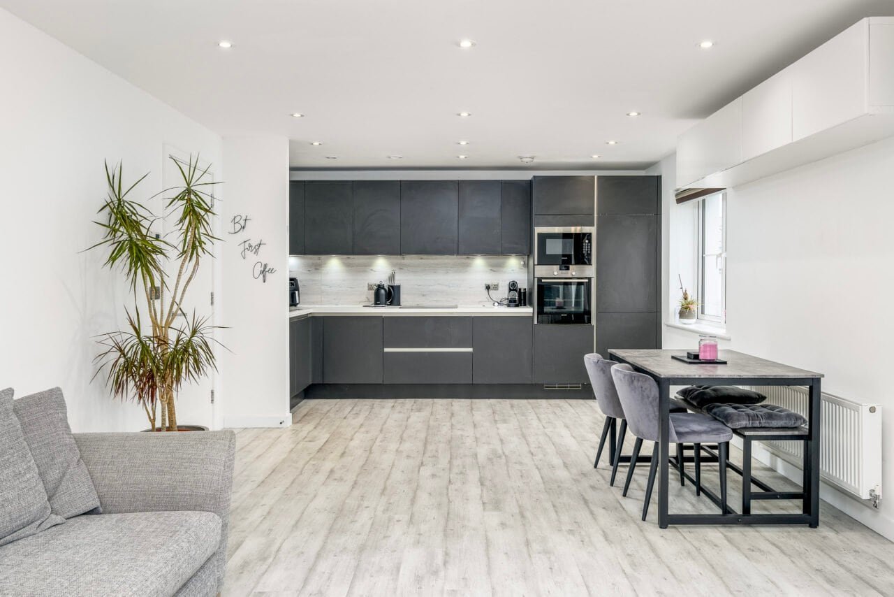 Modern grey kitchen with dining area and large window in contemporary home.