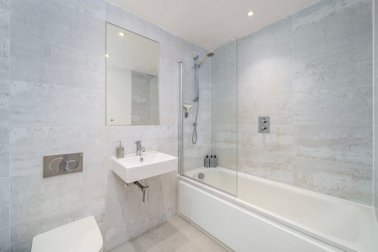 A modern bathroom with a bathtub, shower, and white fixtures in a contemporary design.