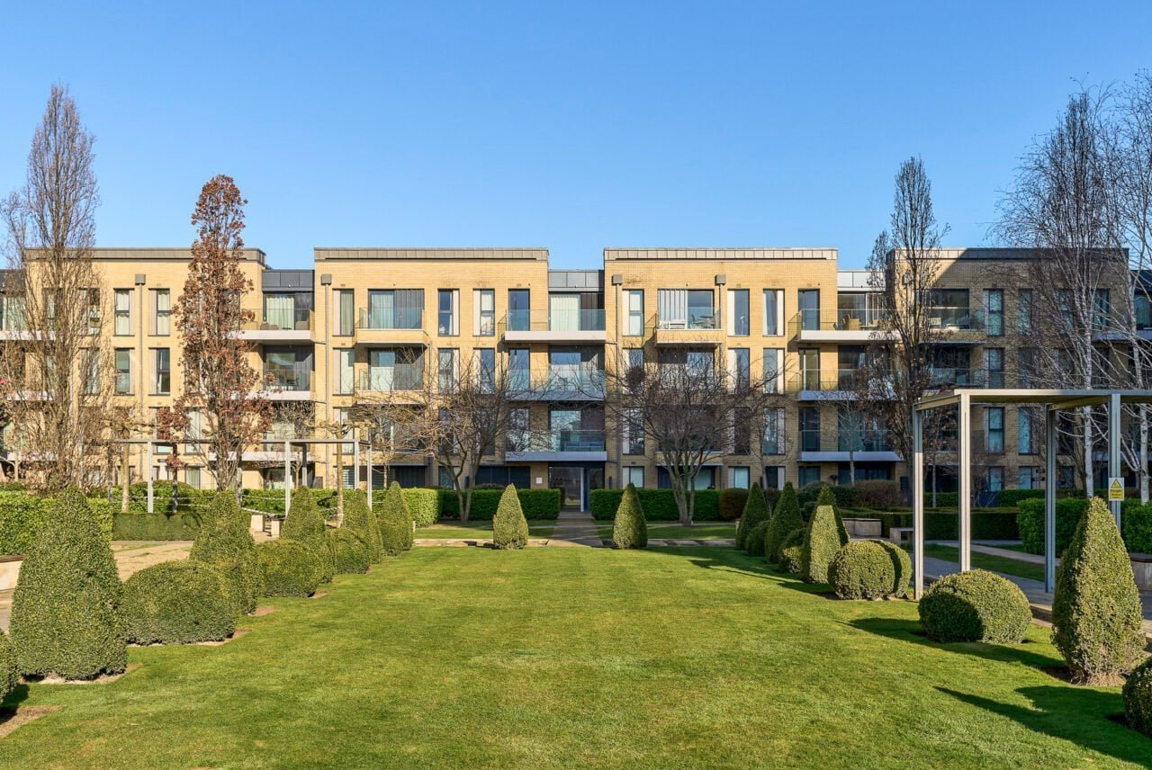 Modern residential apartment complex with landscaped gardens and outdoor seating.