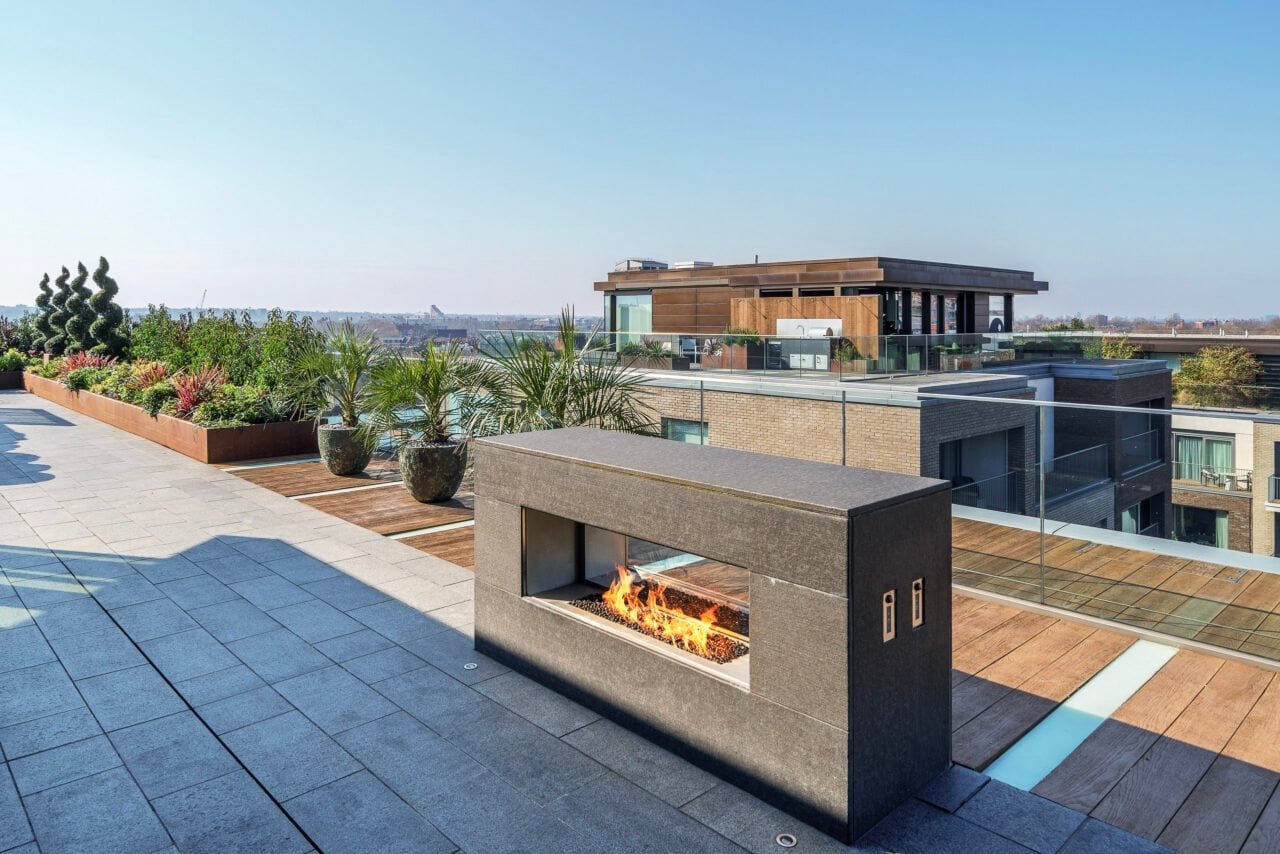 A modern rooftop terrace with outdoor fireplace and city views in London.