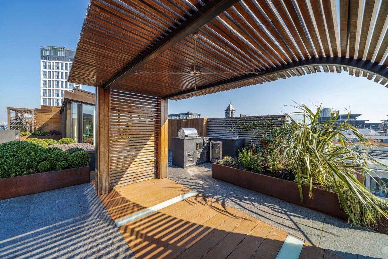 Balcony terrace with wooden pergola, outdoor grill, and city views in London.