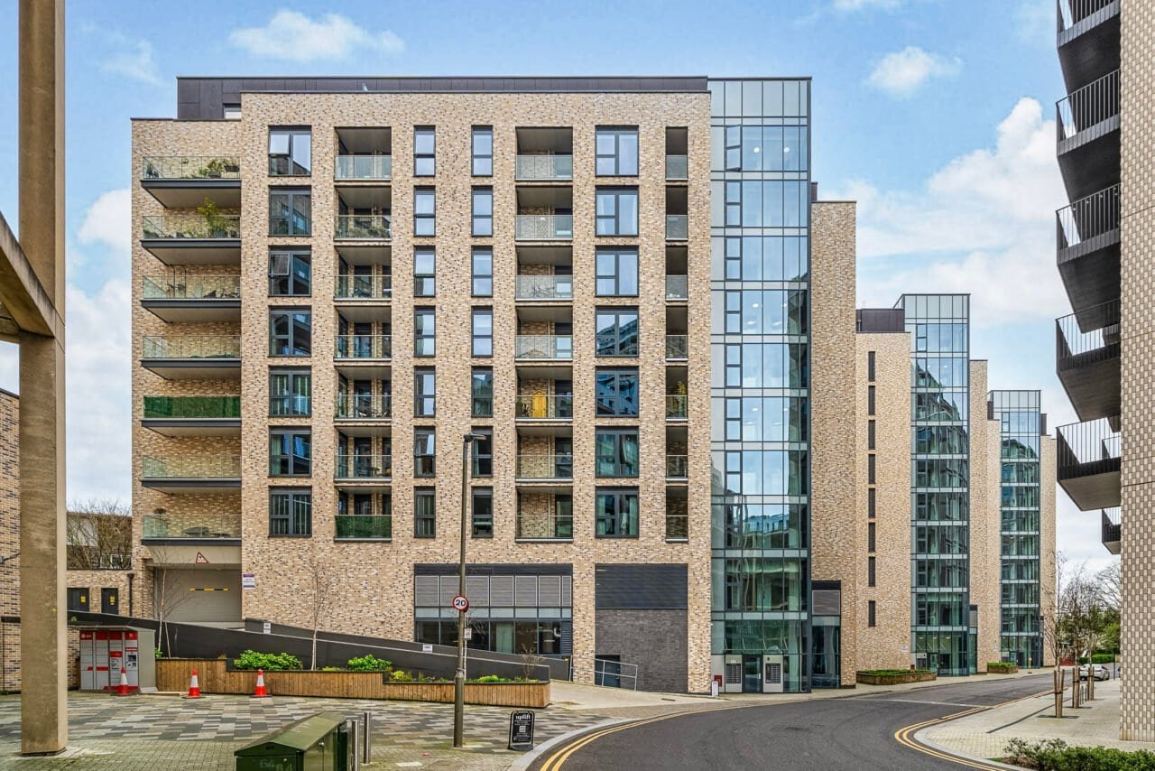 Modern residential apartment building with brick facade and glass balconies.