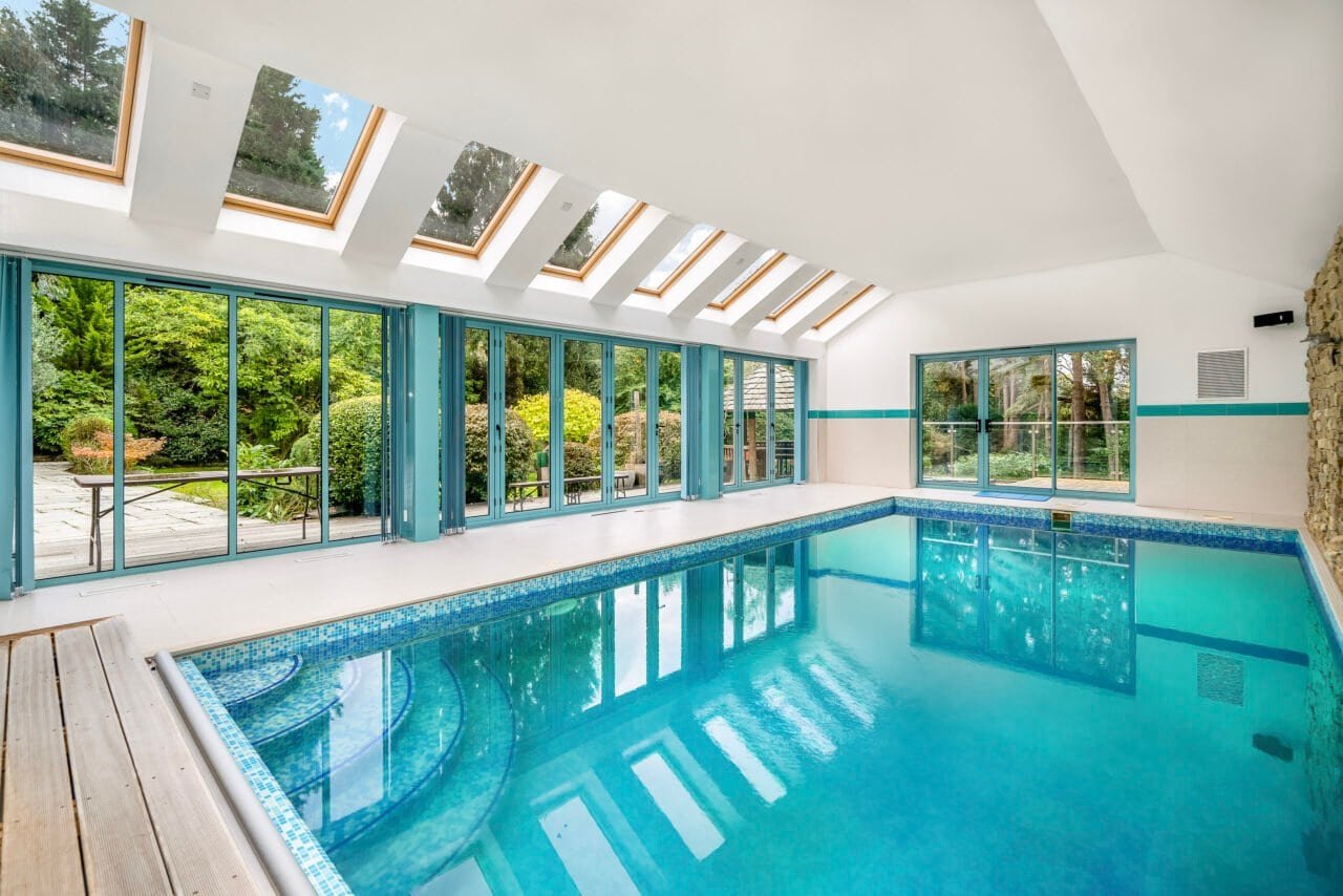 Indoor swimming pool with large glass windows and skylights, modern home leisure area.