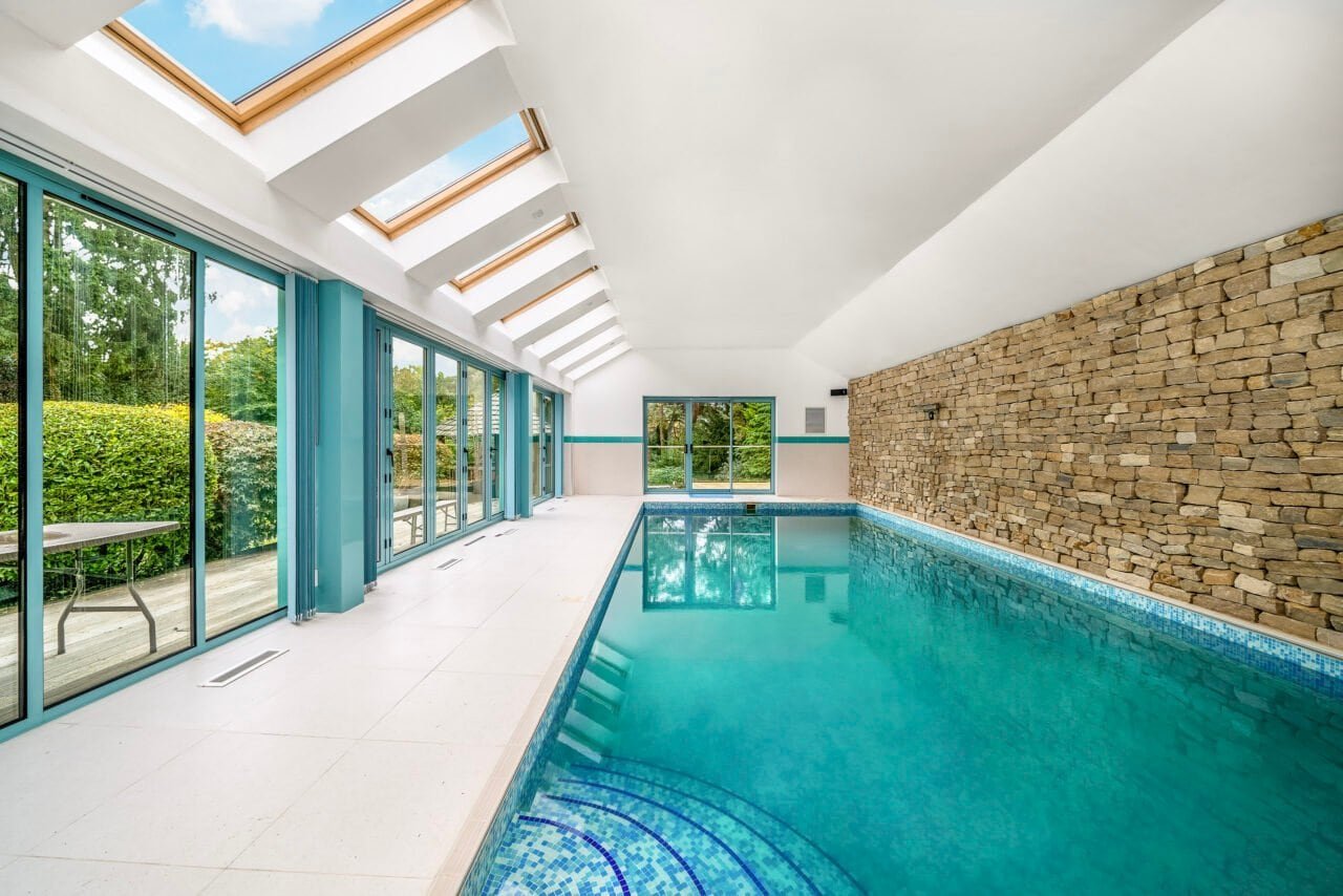 Indoor swimming pool with large skylights and glass doors, modern home leisure area.