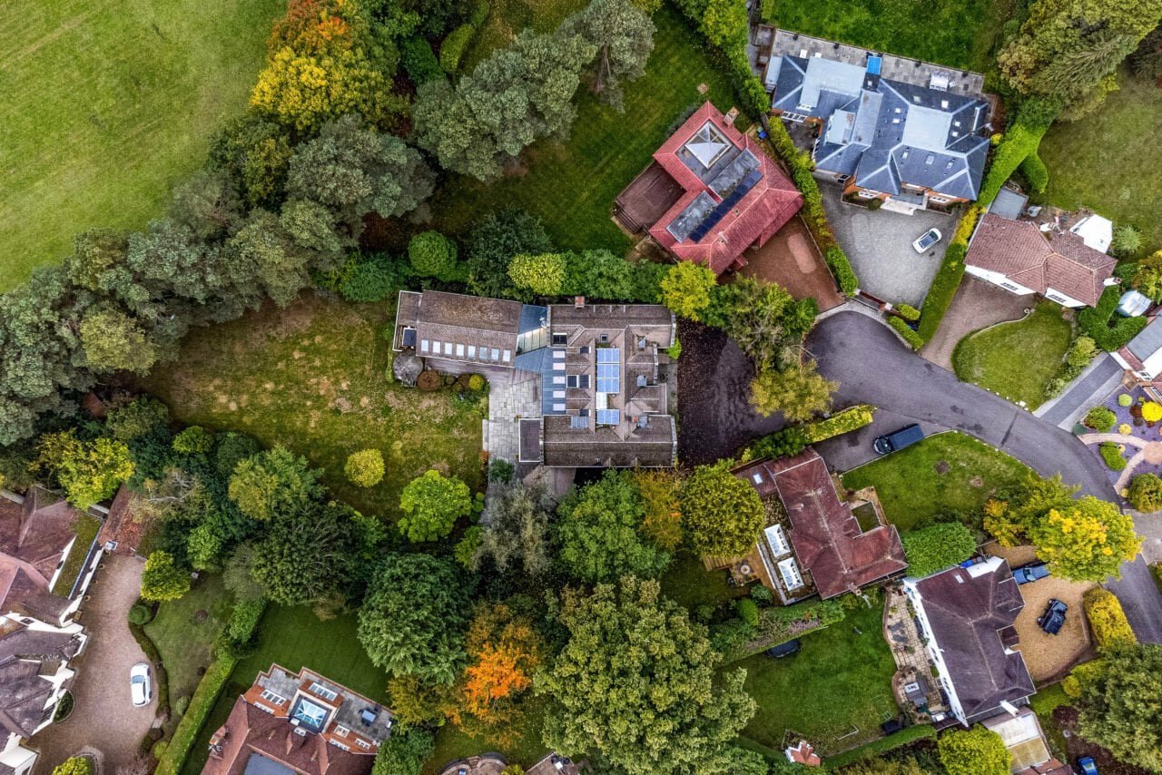 Aerial view of residential houses surrounded by trees and greenery in a neighbourhood.