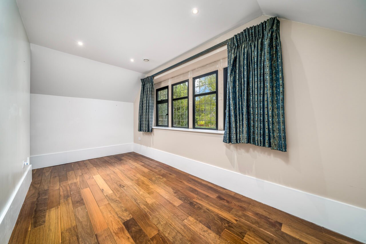 A spacious empty room with large window and wooden floor, ideal for home living.