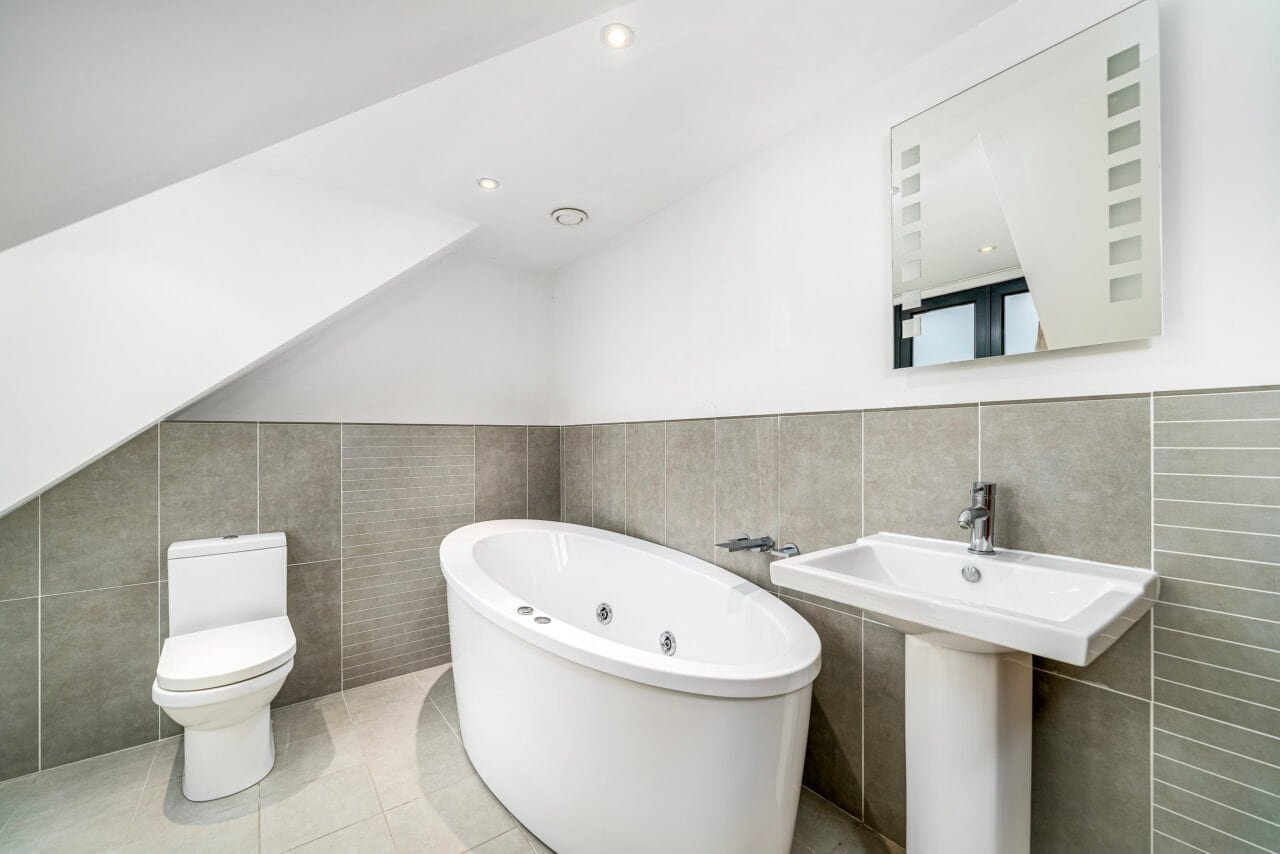 A modern bathroom with a toilet, bathtub, and sink in a bright, minimalist space.
