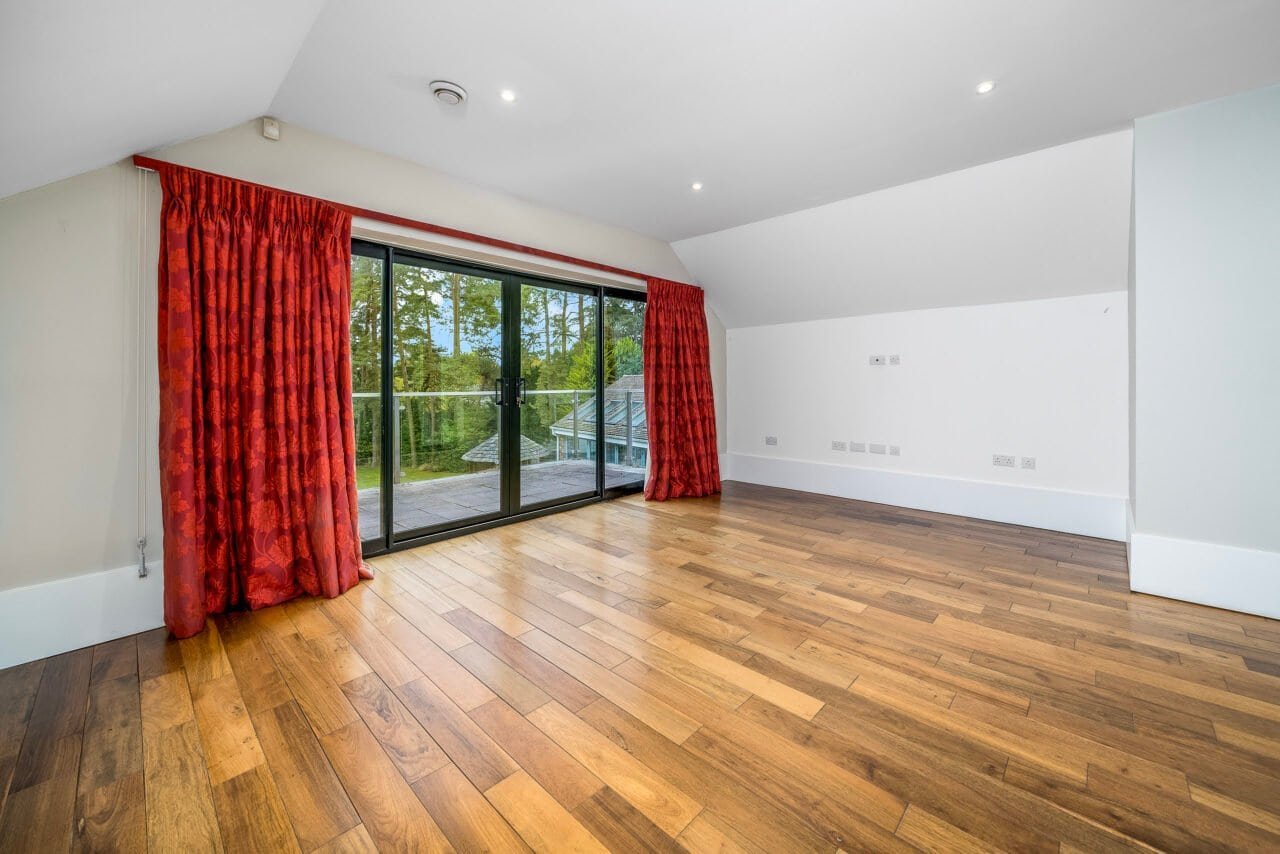 A spacious living room with large glass doors and wooden flooring, bright and modern.