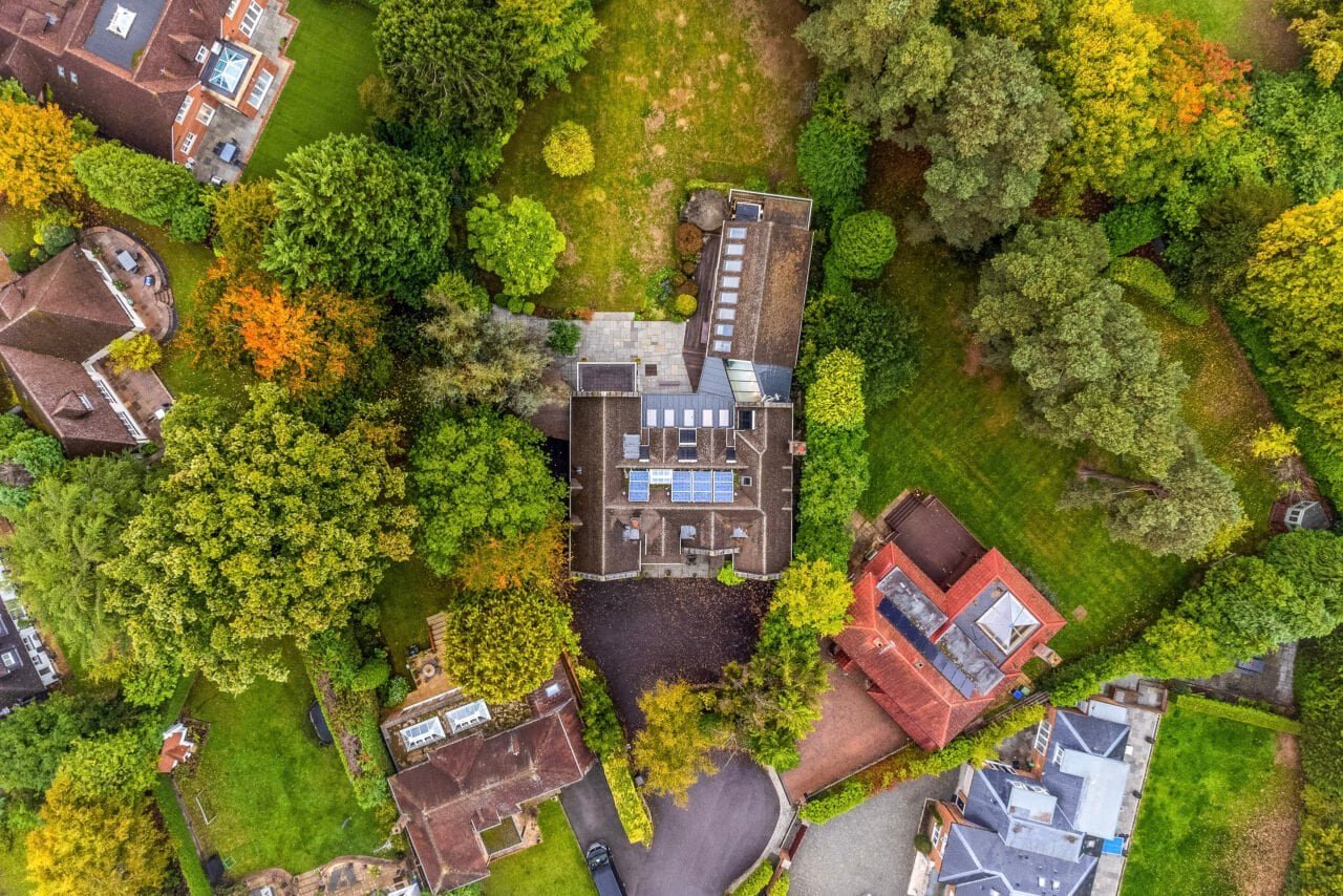 Aerial view of a residential property surrounded by lush greenery and mature trees.