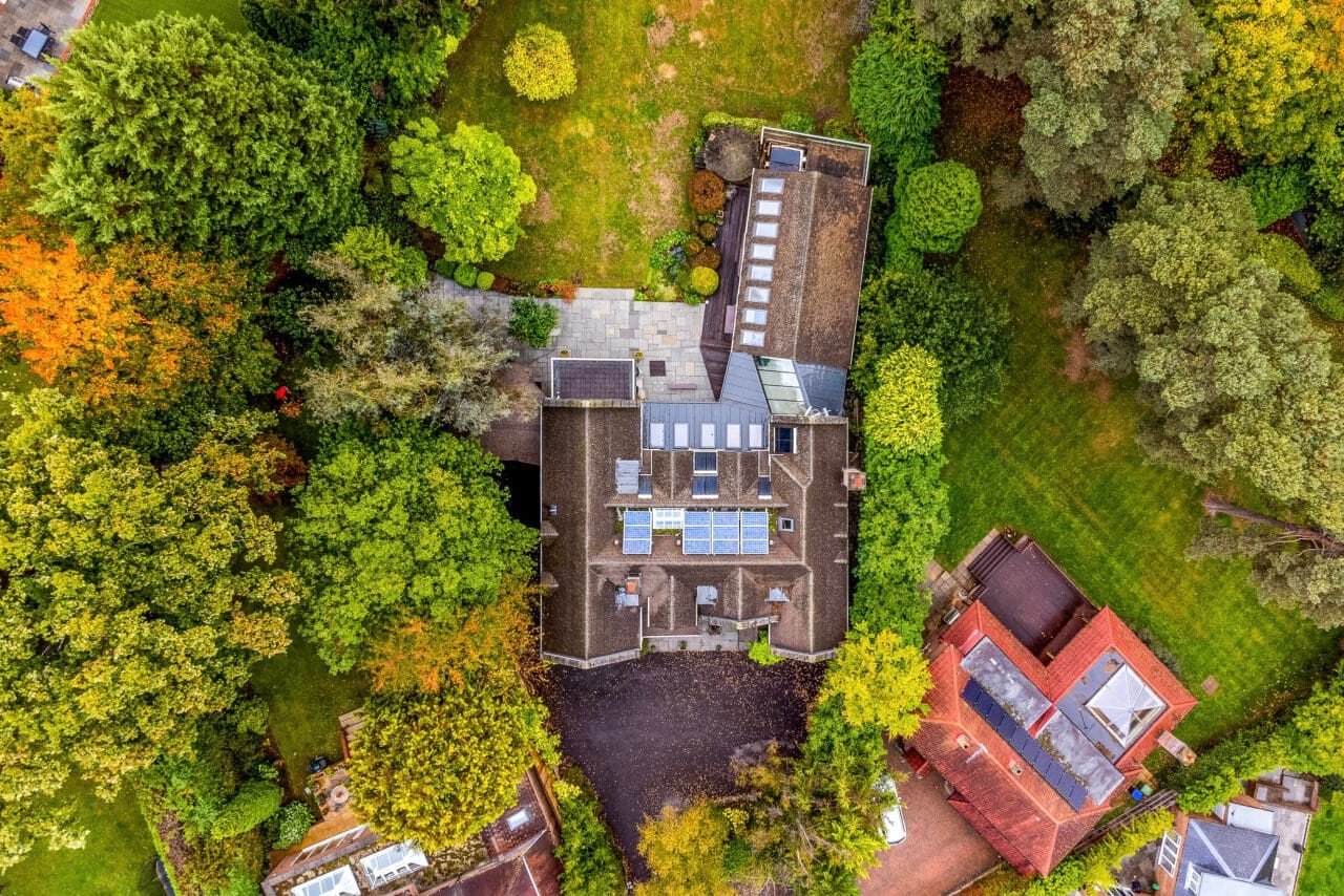 Aerial view of a modern house surrounded by lush green trees and garden.
