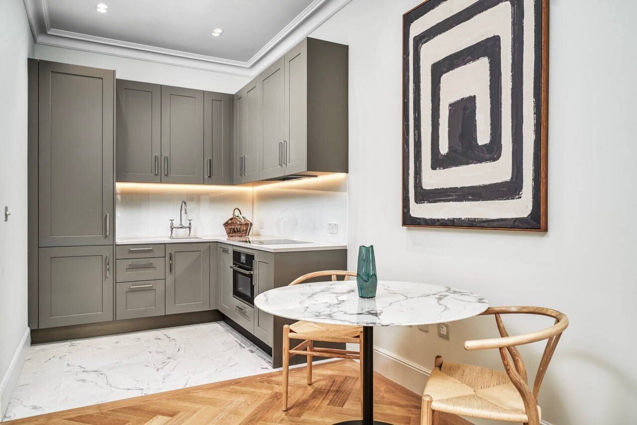 A modern grey kitchen with marble dining table and wooden chairs, minimalist decor.