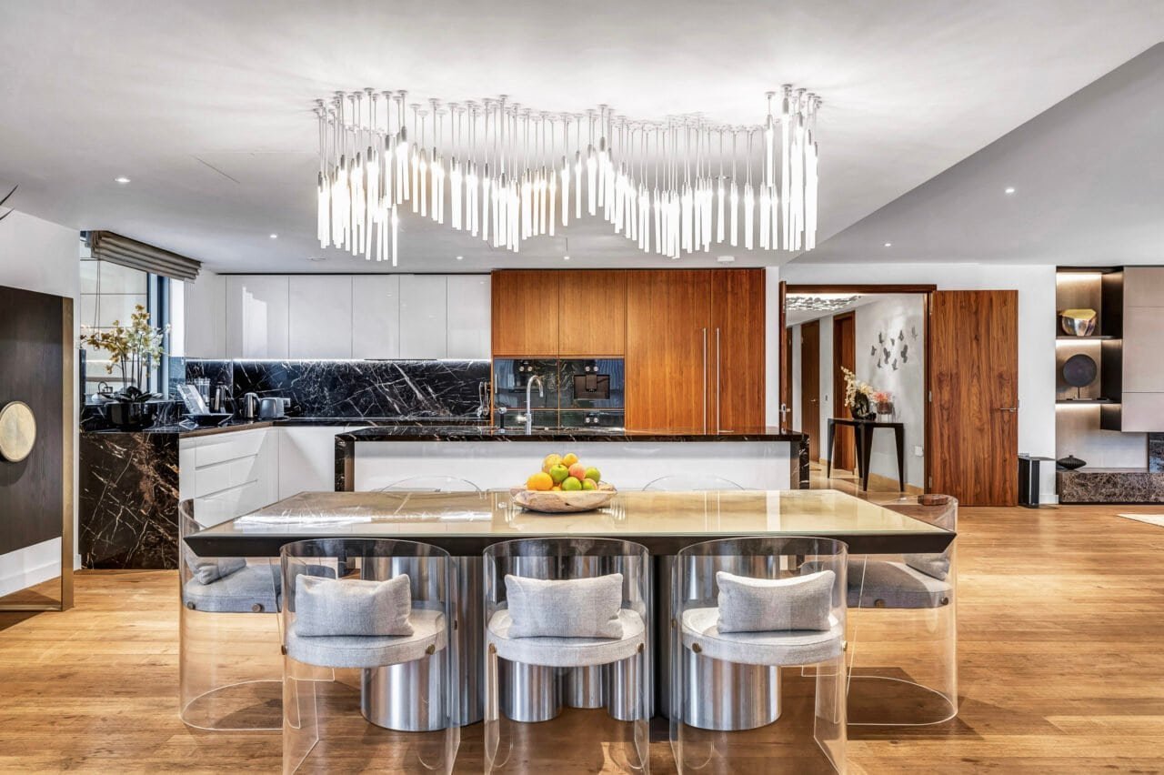 Modern open-plan kitchen with marble island, stylish lighting, and wooden accents.