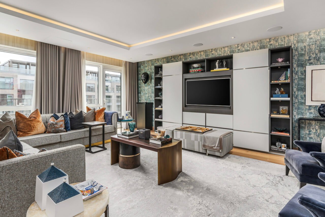 A modern living room with a large TV, stylish furniture, and decorative shelving.