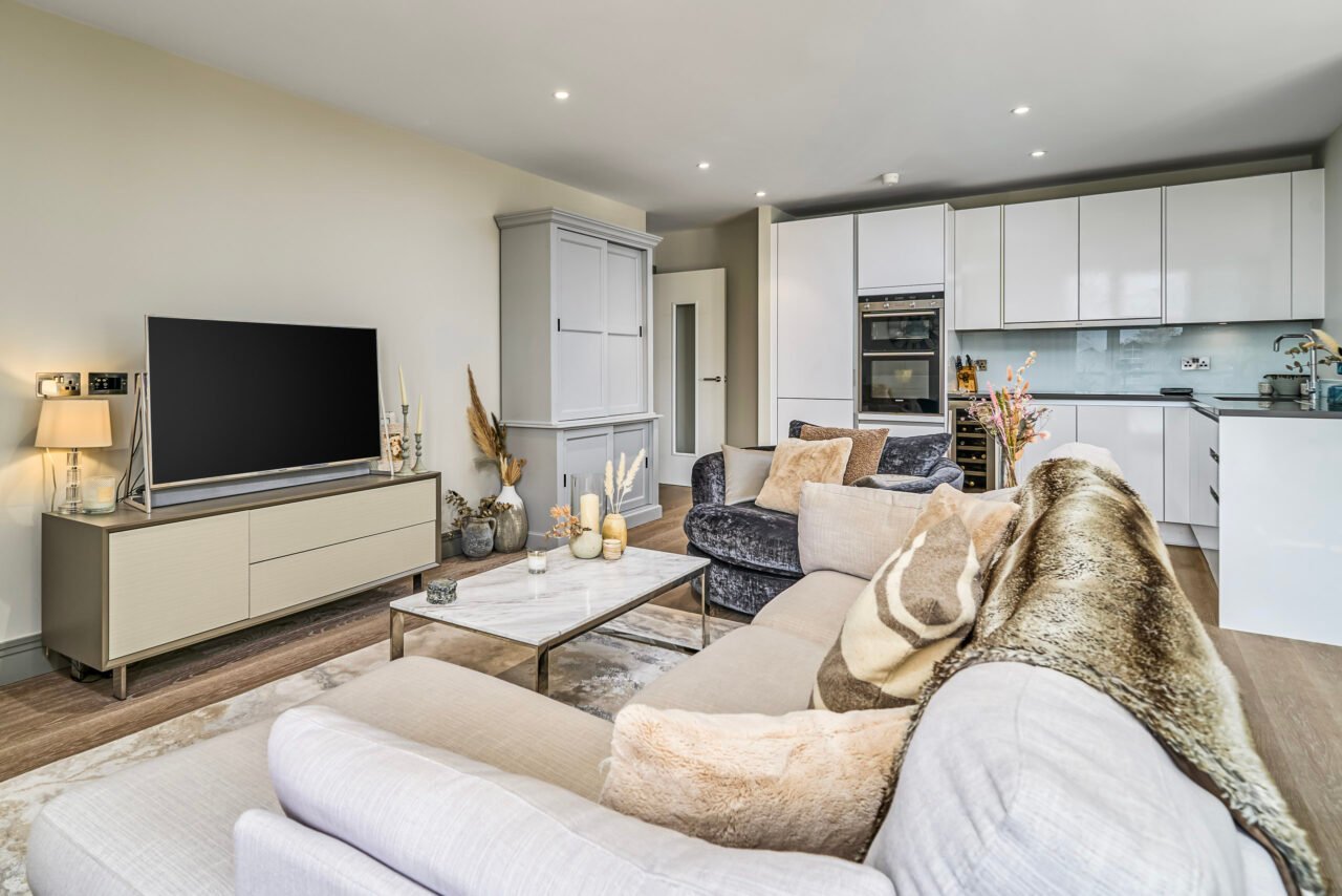 Modern open-plan living room with white kitchen and cosy seating area.