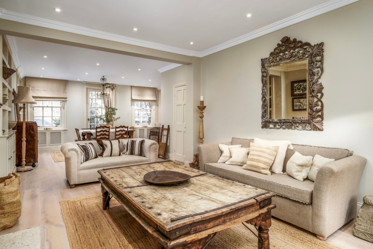 A cozy living room with beige sofas, wooden coffee table, and decorative mirror.