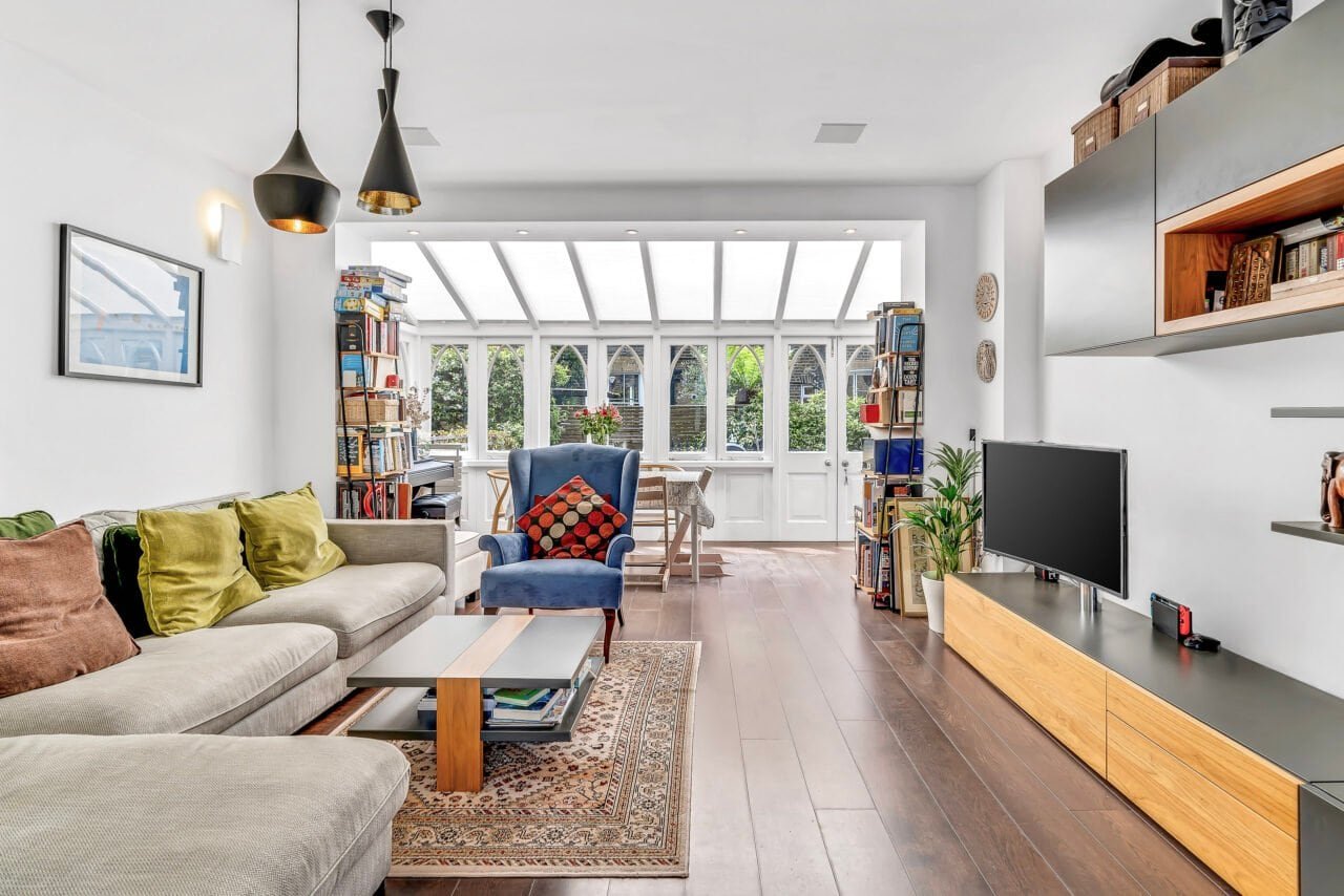 A cosy living room with large bay window, modern furniture and wooden flooring.